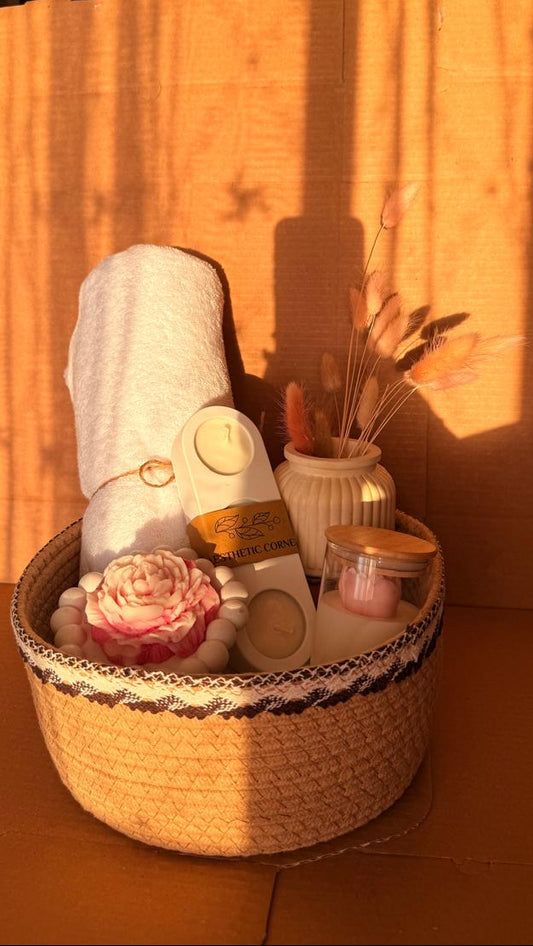 Decorative basket with a towel, bottle, and small plants against a wooden wall.